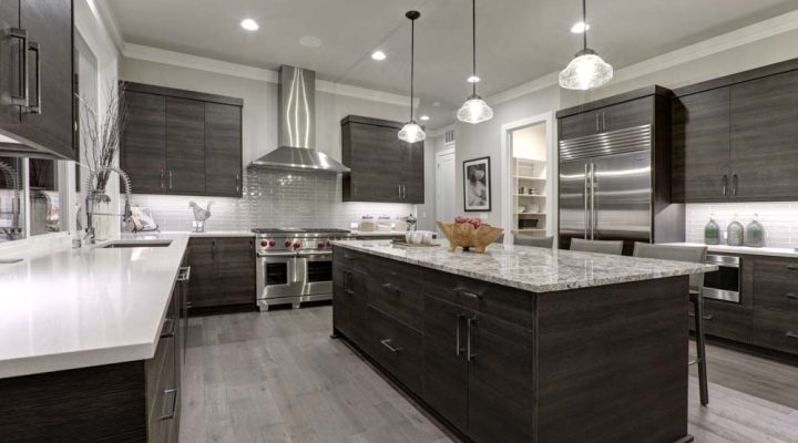 A sleek, contemporary kitchen featuring dark cabinetry, stainless steel appliances, and recessed ceiling lighting.
