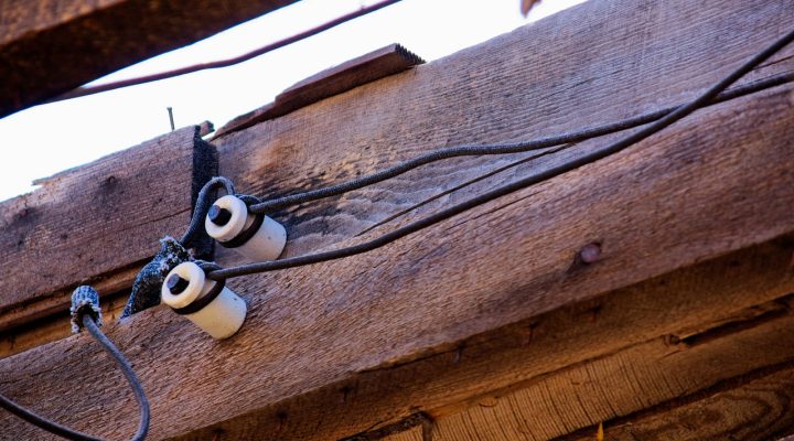 Vintage knob-and-tube wiring installed along wooden beams, showcasing its historical design and insulation method.