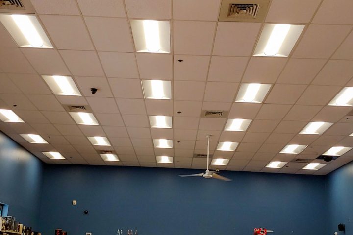 A store interior with bright, evenly distributed ceiling lights and a central ceiling fan for air circulation.