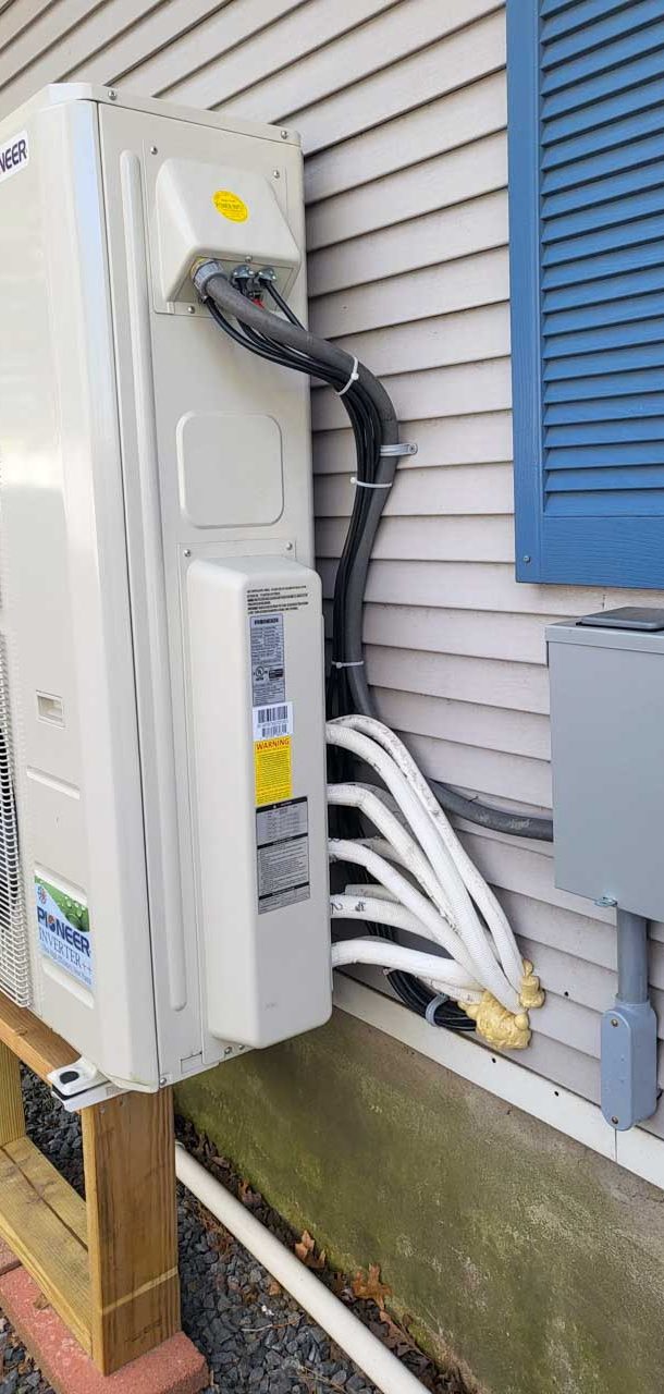 A Pioneer inverter heat pump unit mounted on the side of a house, with neatly organized cables and wiring.